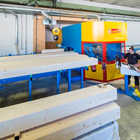 Automatisierte Zuführung und Abtransport des Werkstücks erleichtern die körperliche Arbeit der Mitarbeiter in der Produktion bei i+R Holzbau. © ©Petra Rainer